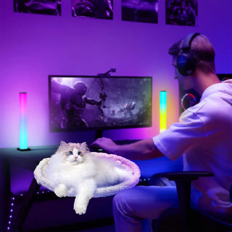Cat resting comfortably in a FelRelWel cat desk bed on a gaming desk with colorful LED lights